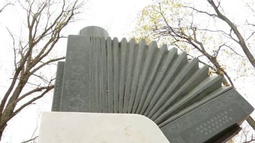 Алые розы у подножия памятного знака